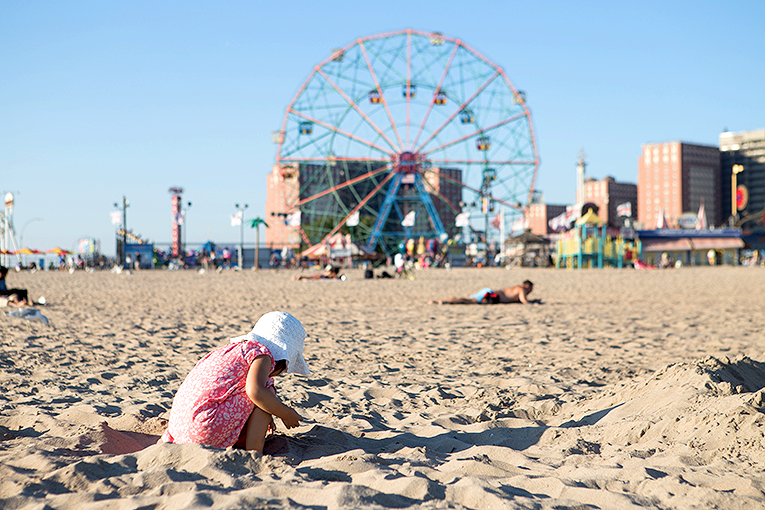 Bild på liten flicka som leker i sanden på Coney Islands strand