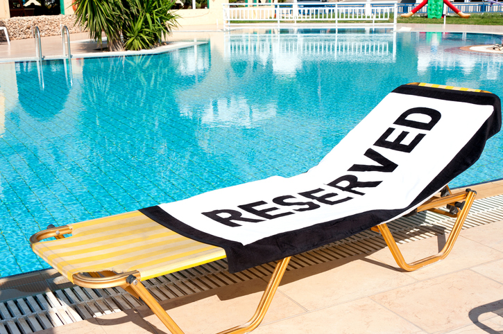 Lounge chair next to pool with 'Reserved' towel